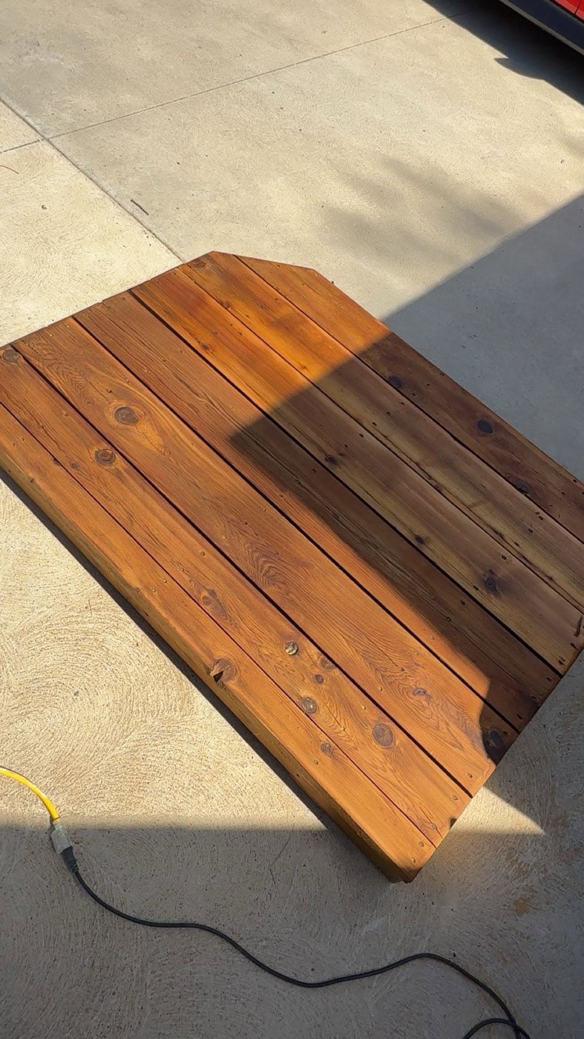 A single board laid on concrete with stain brushed across part of it, the untreated timber left showing alongside for comparison