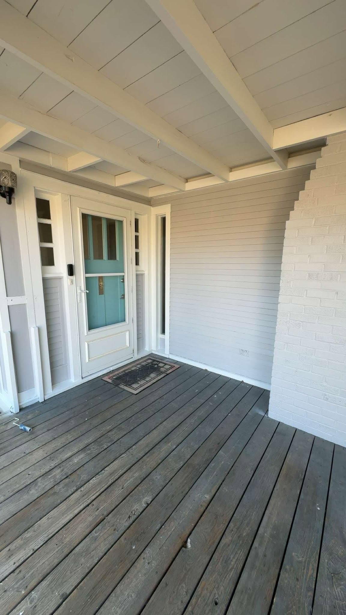 Weathered gray deck boards on a covered porch, the timber silvered and the grain lifting