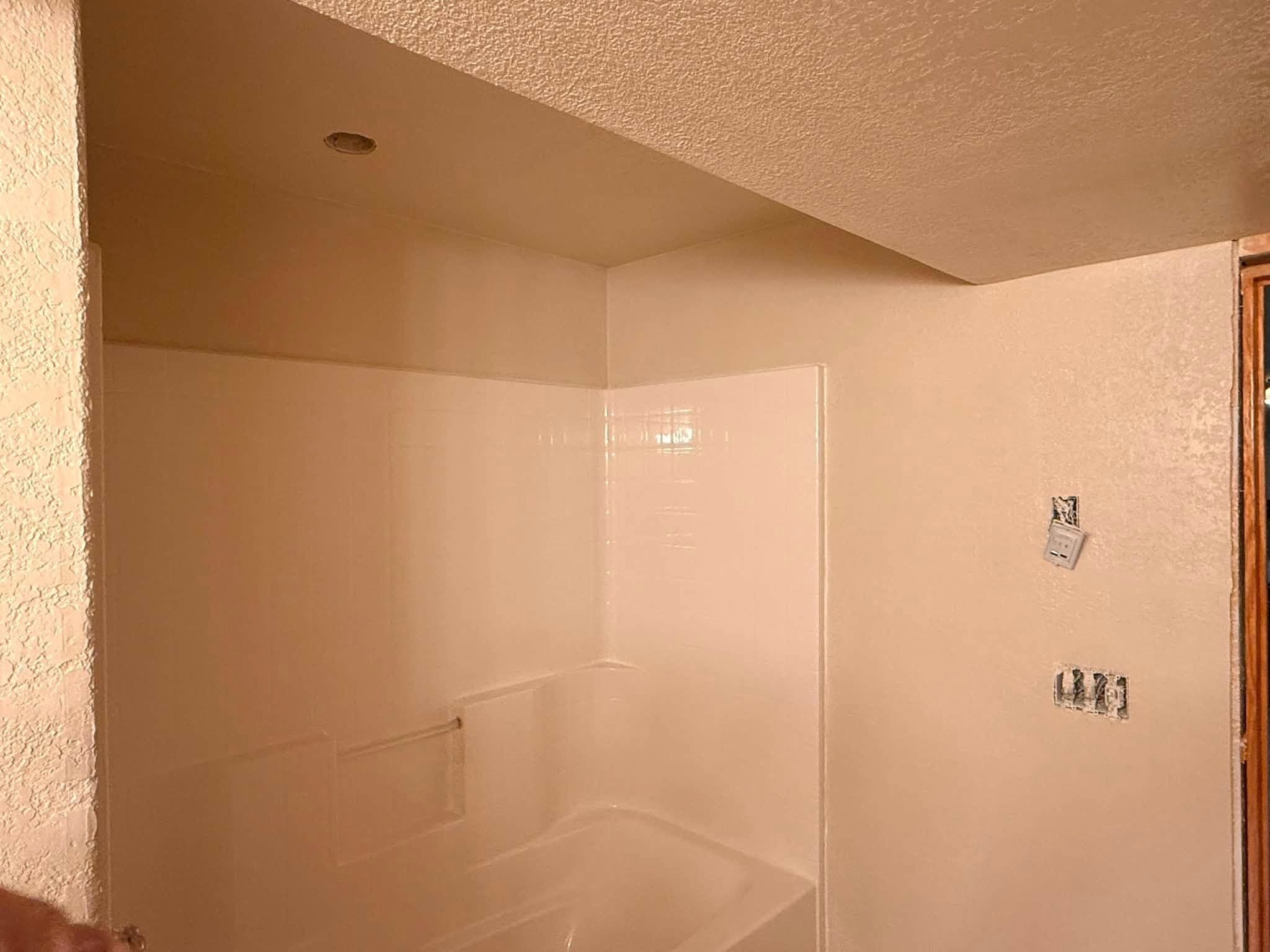 A shower alcove made good and painted, smooth walls with the plumbing outlets capped off