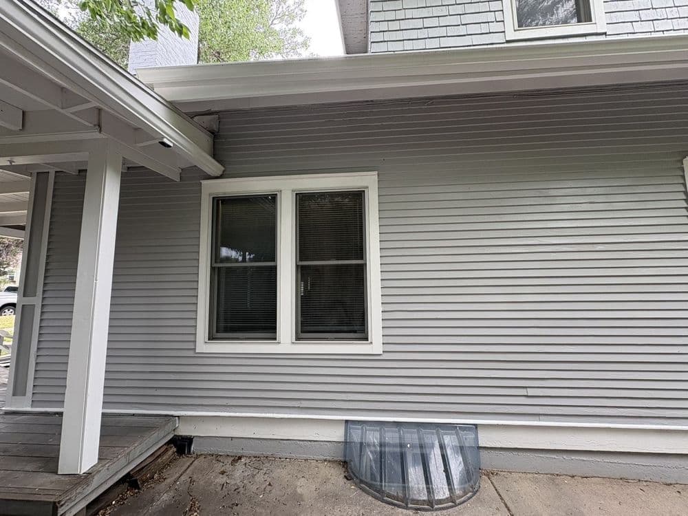 Exterior elevation in light gray lap siding with crisp white window and corner trim, soffit and porch column