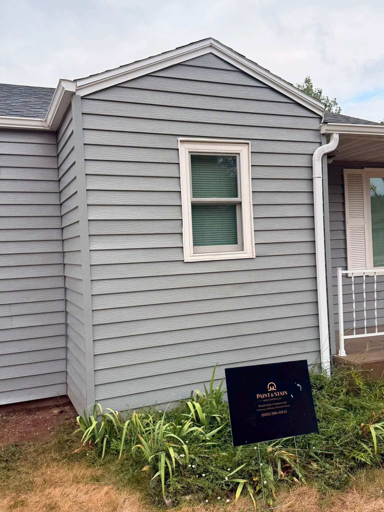 Finished gable end and downspout in gray with white trim