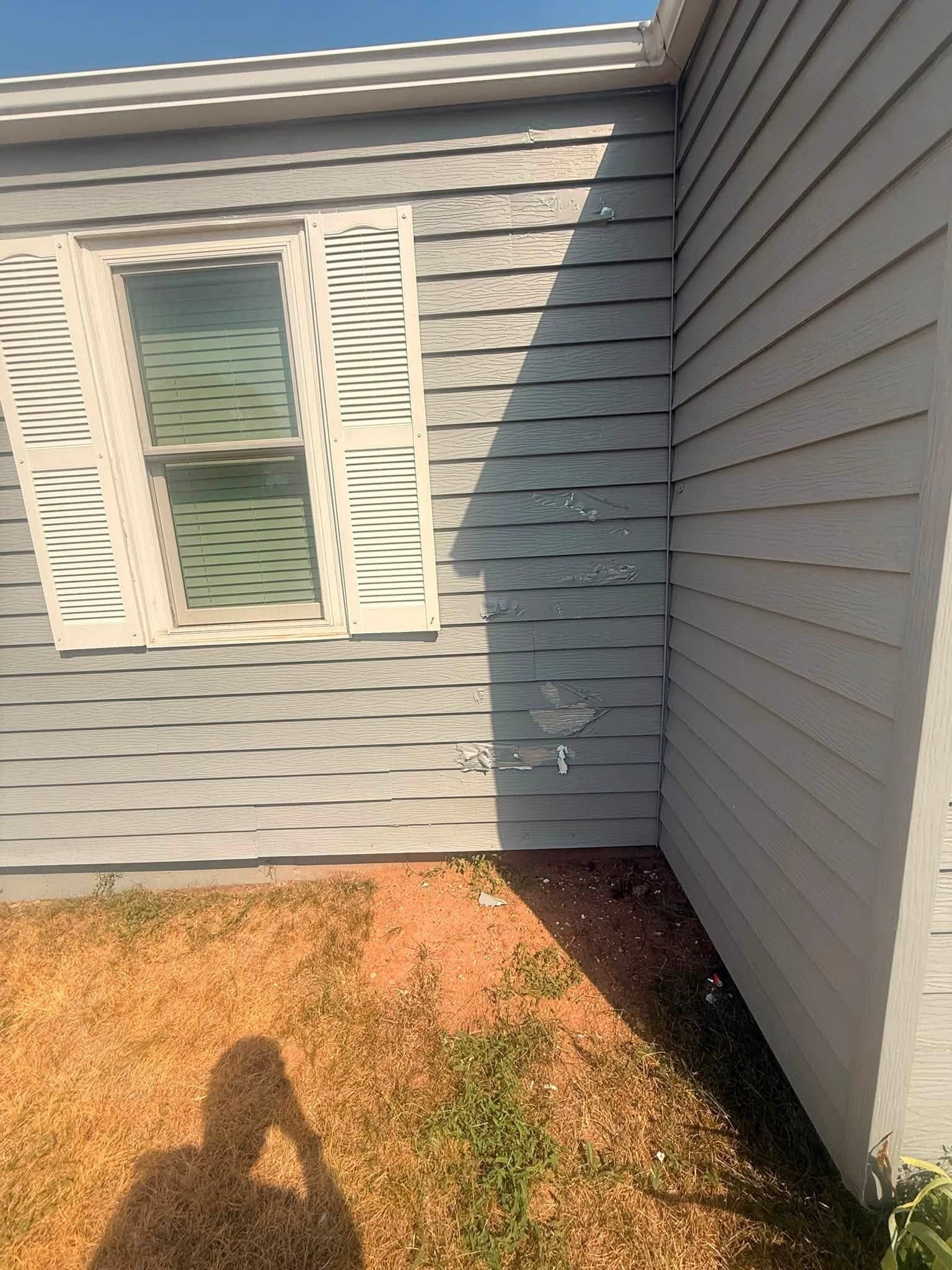 A finished corner elevation in gray with white trim and a louvered shutter, the gable returning above