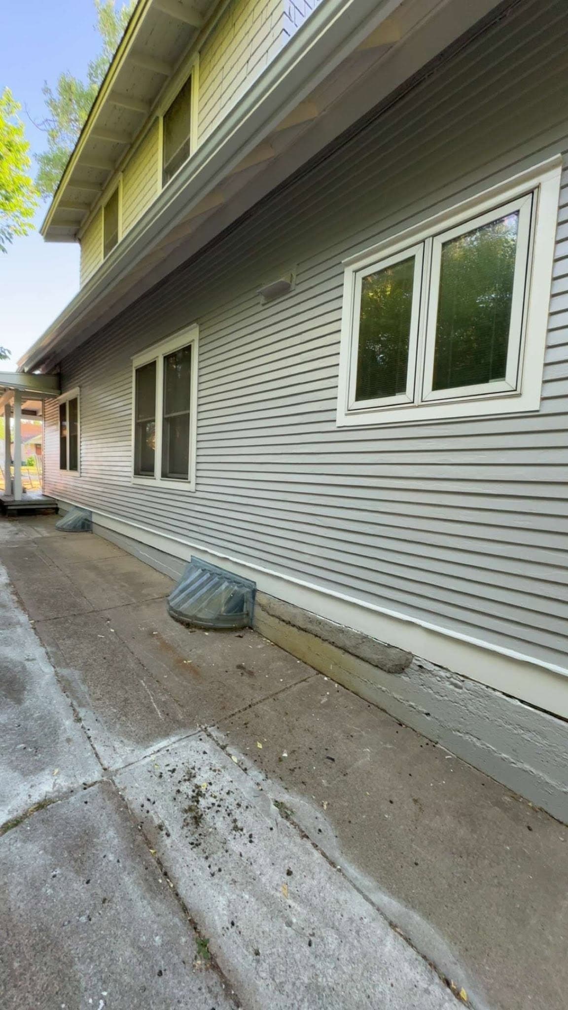 A finished elevation in sage green with white window trim, running back along a concrete path