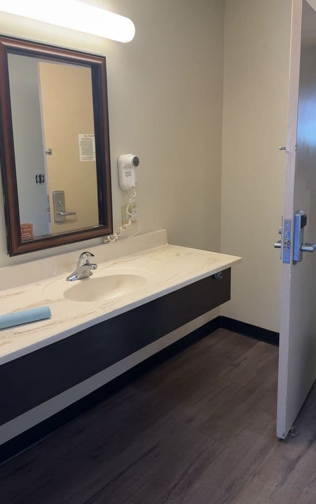 Bathroom vanity with a stone-look top over a dark base, a framed mirror and a vanity light in a finished bath