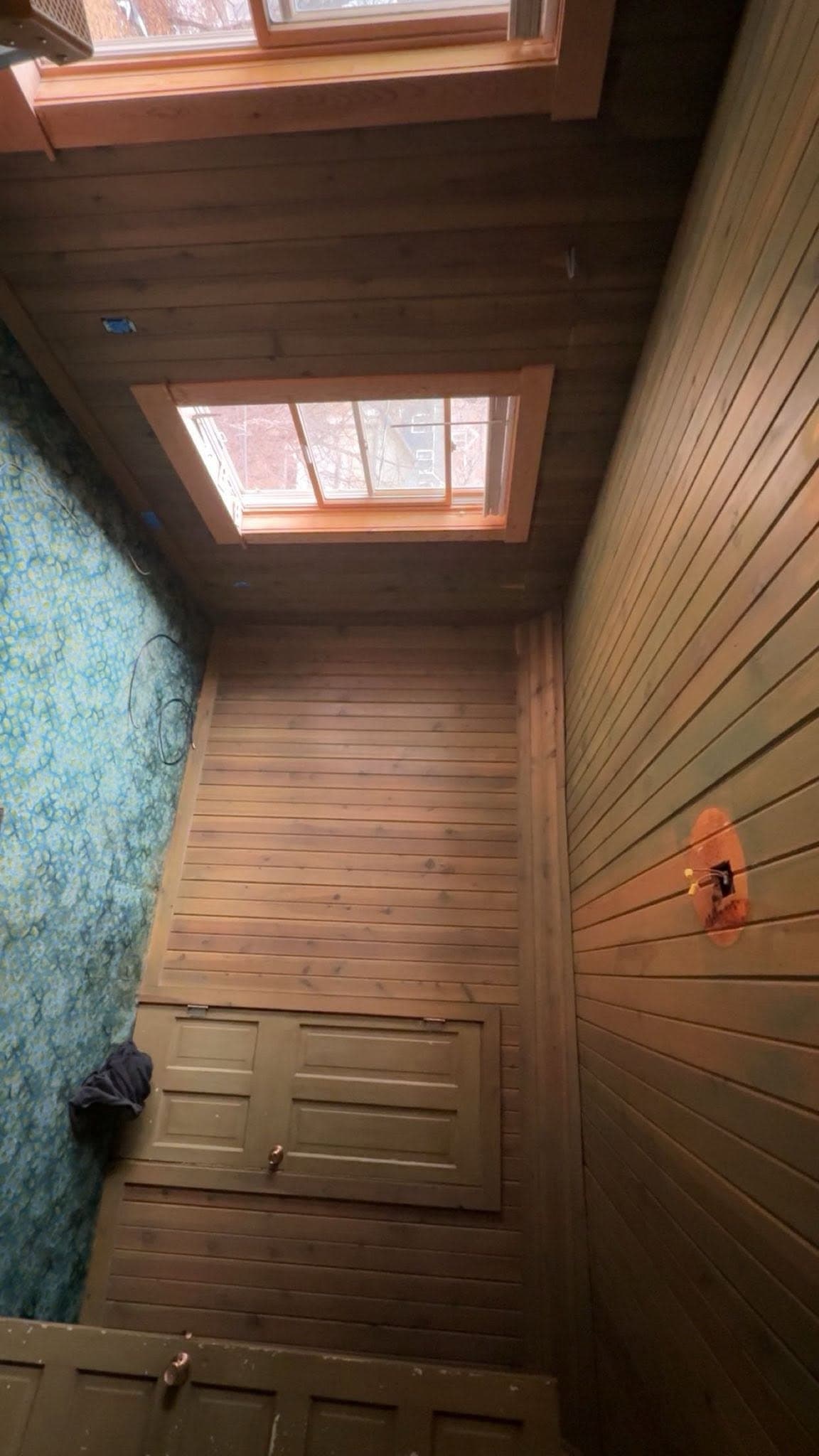 A cedar-lined room with a skylight overhead and a louvered timber door
