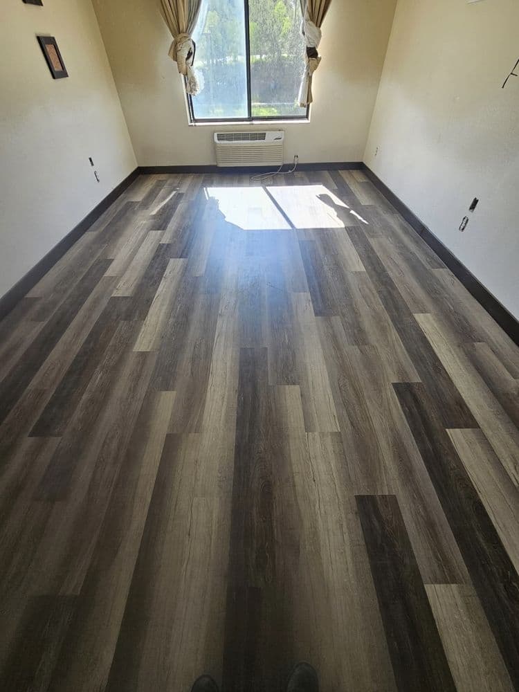 Finished room at the end of a job: painted walls, a curtained window and plank flooring